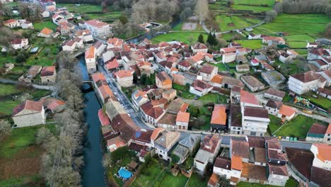 Drone-orbit-around-quaint-spanish-village-built-up-around-Molgas-river-in-Ourense