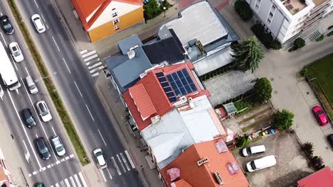 Solar-panels-on-red-roofed-building-in-town-center,-aerial-view