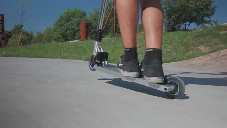 Low-angle-view-of-stunt-scooter-rider-stand-on-deck-and-perform-wheelie