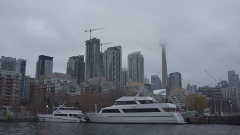Yachten-Vertäuten-In-Einem-Hafen-Von-Toronto-Mit-Dem-CN-Tower,-Der-In-Nebel-Und-Stadtkulisse-Gehüllt-Ist