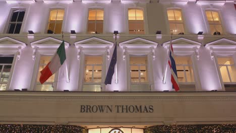 Banderas-En-El-Edificio-De-Los-Grandes-Almacenes-Brown-Thomas-Por-La-Noche-En-Dublín,-Irlanda