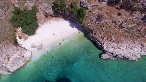 Retreating-overhead-drone-shot-of-Agriosiko-Beach,-a-secret-getaway-in-Cephalonia,-off-the-coast-of-Greece-in-the-Ionian-islands