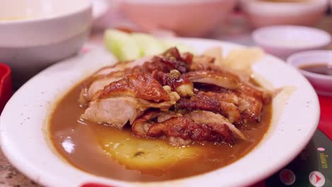 Ein-Stück-Peking-Ente-In-Eine-Würzige-Sauce-Tauchen,-Die-Auf-Einer-Platte-In-Einem-Restaurant-In-Bangkok,-Thailand,-Serviert-Wird