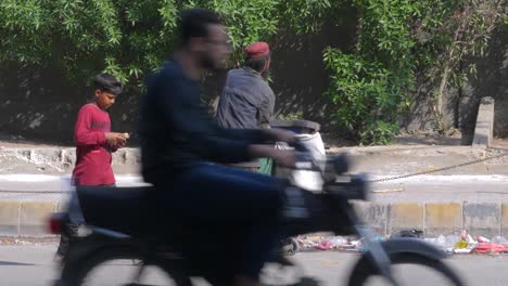A-slow-motion-closeup-shot-of-a-garbage-collector-picking-up-wastes-and-garbage's-from-a-dustbin-at-side-of-a-street-in-Saddar-Bazar-Street-of-Karachi-,-Pakistan