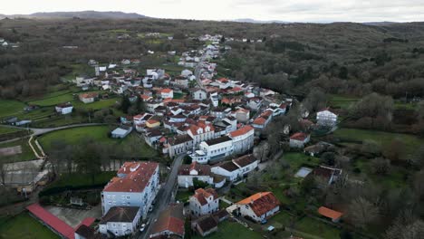 Drone-dolly-descends-above-white-buildings-on-river-Molgas-in-quaint-village-in-Spanish-countryside