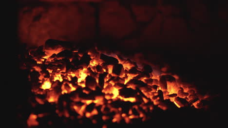 Fiery-coals-in-dark-stove,-nighttime-heat-source-close-up