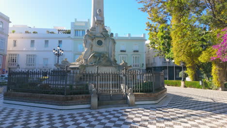 Monumental-statue-in-a-plaza-with-green-trees-Monument-to-the-Marquis-de-Comillas-in-Cádiz,-Spain