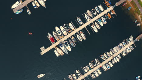 Drone-view-of-the-marina-with-moored-yachts-and-motorboats-and-small-yacht-sailing-in-the-middle