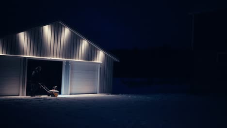 Man-Using-Snowblowing-Machine-In-Removing-Snow-Outside-Barn-At-Night