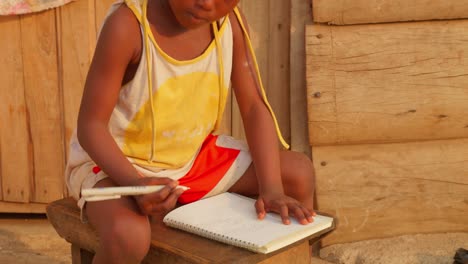 Niño-Africano-Estudiando-En-La-Escuela-De-Una-Aldea-Pobre-Y-Remota,-Escribiendo-Notas-Y-Aprendiendo-A-Escribir-Y-Leer