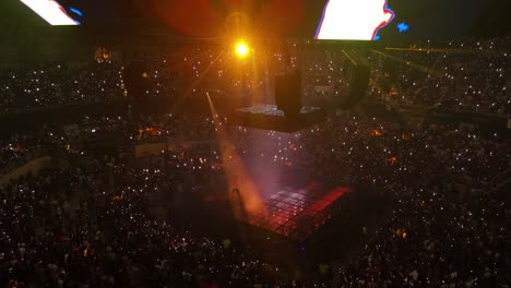 Drone-establishing-shot-of-stage-with-singing-Eladio-Carrion-during-concert-with-flashing-lights-and-crowd-of-fans