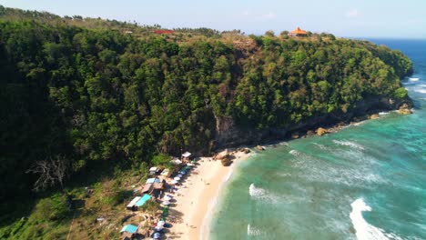 Drone-Descending-on-Sand-Atuh-Beach,-Flying-Towards-Limestone-Steep-Cliff-in-Nusa-Penida,-Bali,-Indonesia