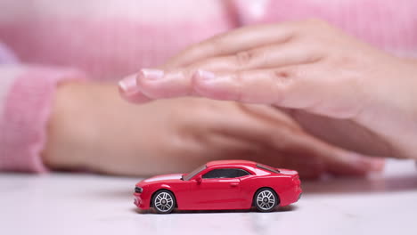 Die-Hand-Schwebt-über-Einem-Roten-Spielzeugsportwagen-Und-Zeigt-Den-Wunsch,-Durch-Einen-Autokredit-Ein-Neues-Fahrzeug-Zu-Besitzen