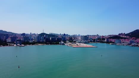 Aerial-view-flying-towards-shore-with-beatiful-skyline-fro-sea-in-Weihai---China