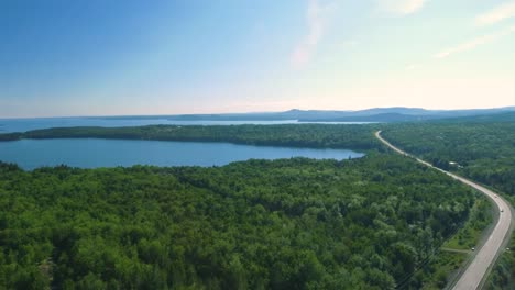 Drone-shot-rising-up-revealing-a-massive-lake-next-to-a-wooded-highway