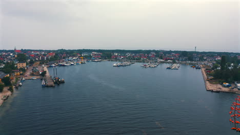 Aerial-view-of-drone-flying-towards-the-marina-with-moored-yachts-and-motorboats