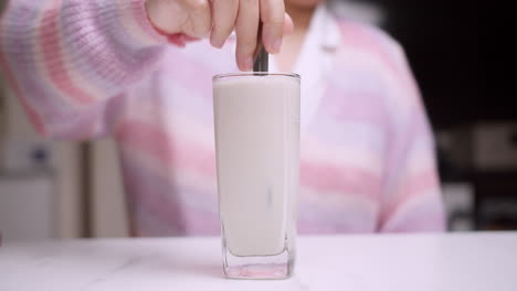 Detail-Einer-Weiblichen-Hand,-Die-Mit-Einer-Gabel-Milch-In-Einer-Glasschale-Rührt