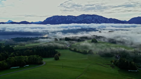Aerial-view-of-a-misty-landscape-with-lush-greenery-and-a-mountain-range-in-the-background