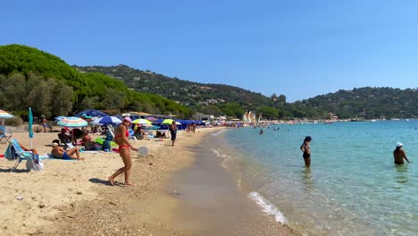 People-enjoying-a-fun-sunny-summer-beach-day-in-Cavalière-Lavandou-South-of-France,-beautiful-transparent-turquoise-water,-holiday-vacation-by-the-sea,-4K-shot
