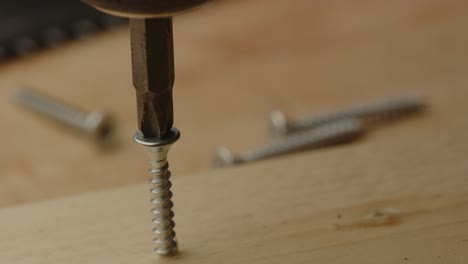 Close-up-of-electric-screw-driver-drilling-out-screw-of-wooden-board