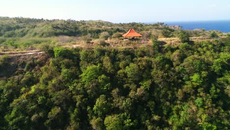 Orangefarbener-Dachschuppen-Auf-Tropischen-Hügeln-In-Der-Nähe-Des-Atuh-Strandes-In-Nusa-Penida,-Bali---Luftaufnahme