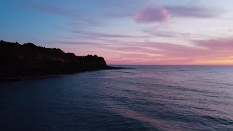 Cliffside-allure:-Pink-clouds-adorn-a-sunset-kissed-cliff-in-captivating-stock-footage