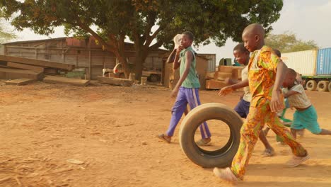 Eine-Gruppe-Kleiner-Kinder-Aus-Afrika-Spielt-Zusammen-Mit-Einem-LKW-Reifenrad-In-Einem-Abgelegenen,-Ländlichen,-Armen-Dorf-Und-Hat-Spaß-Ohne-Spielzeug,-Einfacher-Lebensstil