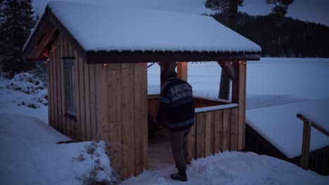 A-Man-is-Making-His-Way-Toward-the-Wooden-Cottage-on-a-Winter-Day-in-Indre-Fosen,-Trondelag-County,-Norway---Static-Shot