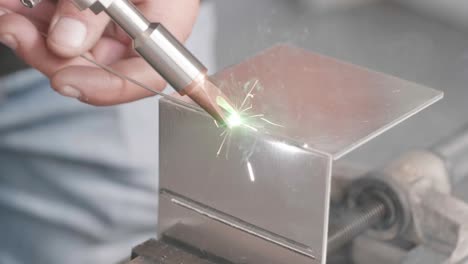 professional-showcasing-laser-welding-device,-connecting-two-rectangular-pieces-of-sheet-metal-while-sparks-fly-using-filling-rod