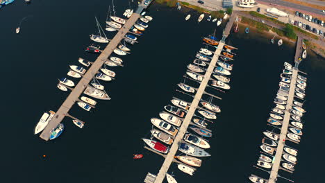 Drone-flying-backwards-in-the-marina-in-Jastarnia,-Poland-with-moored-luxurious-yachts