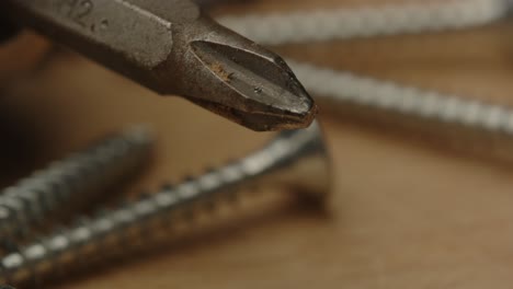 Macro-Pan-of-screws-and-drill-bit-on-a-wooden-surface