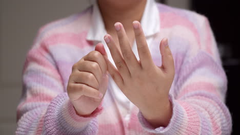 Close-up-of-an-individual-pinching-her-fingers-one-by-one,-massaging-herself-to-relive-the-pain-and-inflammation-she-is-feeling