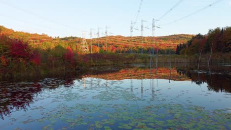 Low-flying-drone-shot-passing-over-the-still-surface-water-of-a-pond-with-a-beautiful-reflection-of-the-surrounding-mountains,-Montréal,-Canada