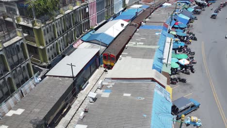 Eine-Drohne,-Die-Einem-Zug-Folgt-Und-über-Den-Mae-Klong-Eisenbahnmarkt-Schießt
