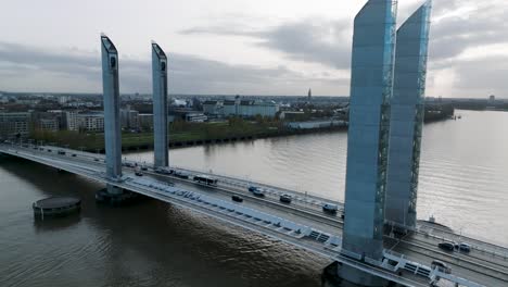 Car-traffic-over-Jacques-Chaban-Delmas-bridge-on-the-Garonne-River-in-Bordeaux-France,-Aerial-dolly-out-reveal-shot