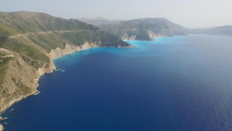 Retreating-drone-shot-moving-overhead-above-the-coast-of-the-peninsula-of-Agriosiko-Beach-located-in-the-island-of-Cephalonia-in-Western-Greece