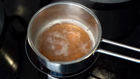 Delicious-Golden-Bone-Broth-simmering-in-small-stainless-steel-pan,-Slow-motion