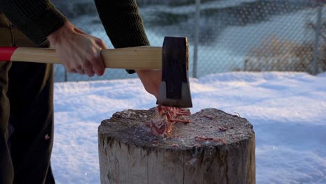 Chopping-Deer-Carcass-Bones-in-Soft-Light,-Snow,-and-Slow-Motion