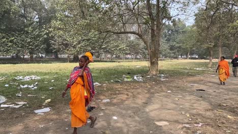 Diagonal-shot-of-woman-wearing-traditional-Indian-attire-and-walking-on-a-pathway-in-Maidan-for-Ganga-Sagar-Mela-during-afternoon-in-Kolkata,-India