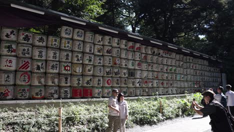 Tourists-Taking-Photos-Beside-Decorative-Wall-Of-Sake-Barrels-Located-At-Meji-Shrine