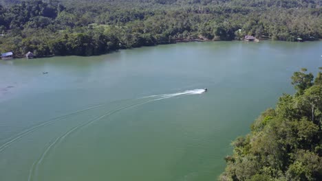 A-motorboat-sails-across-Lake-Izabal-tropical-jungle-of-Guatemala-aerial-view
