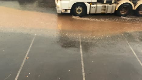 Truck-drive-over-a-dirty-puddle-of-water-in-the-rain,-static-shot