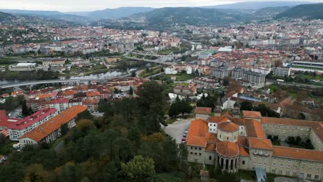Aerial-reveal-of-Ourense-river-and-bridges-to-Catholic-seminary-religious-school-on-hill