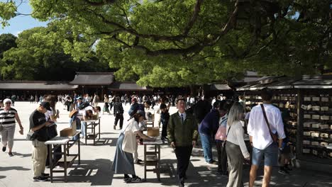 People-signing-prayers-in-Meiji-Shrine-in-Shibuya,-Tokyo,-traditional-ritual,-japanese-culture