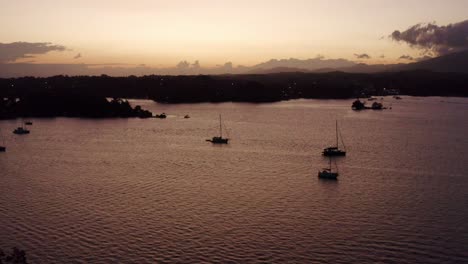 Many-yachts-and-sailboats-anchored-in-Lake-Izabal,-Guatemala-during-dusk,-aerial-view