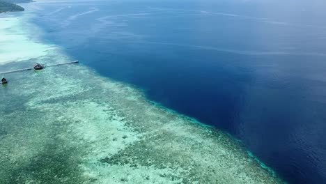 Scenic-aerial-view-of-crystal-clear-ocean-and-coral-reef-ecosystem-in-popular-dive-destination-of-Raja-Ampat,-West-Papua,-Indonesia
