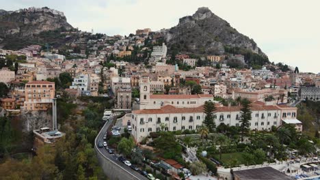 Drohne-Fliegt-Vom-San-Domenico-Hotel-In-Taormina-Weg,-Während-Im-Hintergrund-Gebäude-Auf-Felsen-In-Der-Altstadt-Sichtbar-Sind