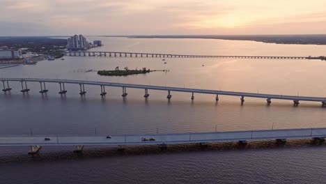 Aerial-backward-view-of-Fort-Myers-Bridge-over-the-ocean-in-Florida,-USA