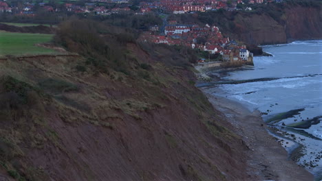 Establishing-Aerial-Shot-of-Sedimentary-Cliffs-and-Robin-Hood's-Bay-UK