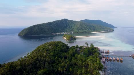 Szenischer-Luftflug-über-Mit-Regenwald-Bedeckte-Tropische-Inseln-Mit-Hütten-Am-Wasser-Mit-Blick-Auf-Das-Meer-In-Raja-Ampat,-West-Papua,-Indonesien